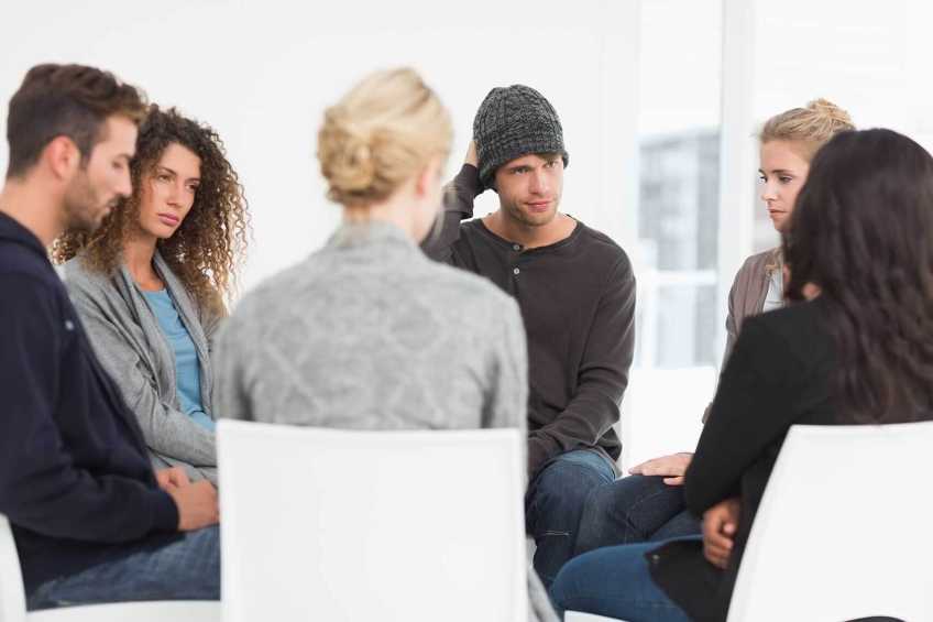 Six young people sitting in a circle in a group session.