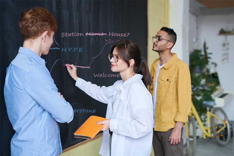 Three young people standing at a chalkboard.
