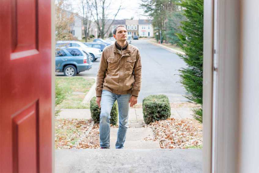 Young man standing in the doorway of a residence