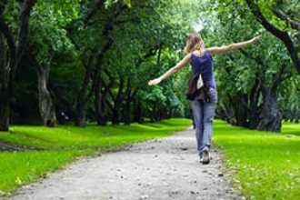 Woman walking along a path with her arms outstretched.